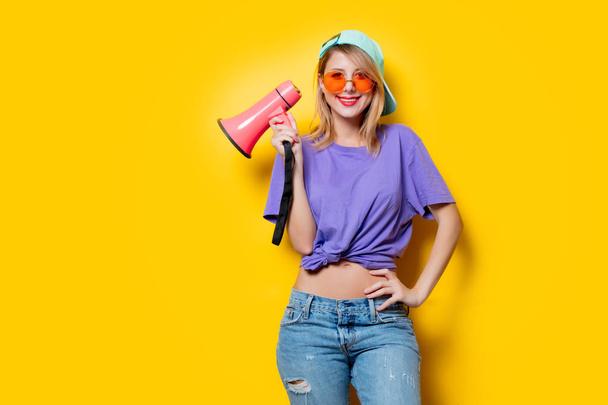 Mladý styl dívka v purpurových šatech s růžovým megafonem na žlutém pozadí. Symbolizuje ženský odpor. Oblečení ve stylu 80. let - Fotografie, Obrázek