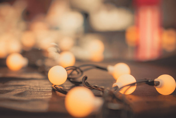 Lumière sélective de lampe de décoration de foyer avec sur la laine noire et le fond flou. Ampoule lumière chaude sur tissu frise noir et brillant. Fond de Noël. ampoule et fil pour fête de nuit
. - Photo, image