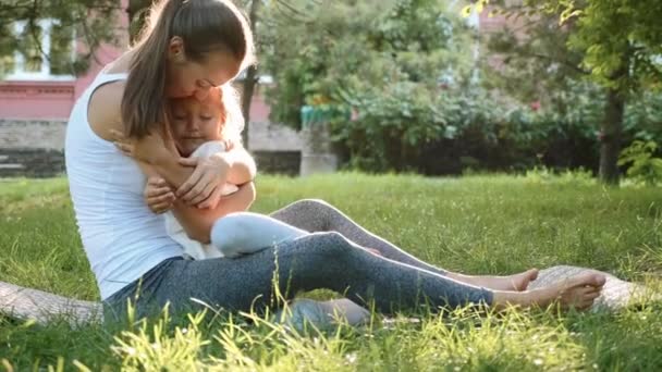 Boldog család fiatal sportos anya és kicsi ravasz lánya szabadban szórakozik - Felvétel, videó