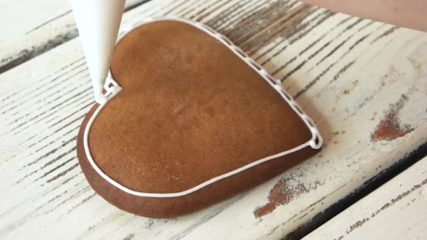 Cukrász díszítése szív alakú keksz. Csővezeték fehér csipke barna szív alakú cookie-t. Kezeli az esküvő napján. - Felvétel, videó