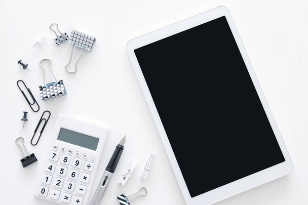 White office desk table with calculator, tablet and other office supplies. Top view - 写真・画像
