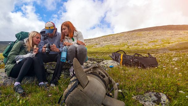 ライフ スタイルと生存の概念のリアビューを旅行します。ハイキングのバックパック、トレッキングを楽しむ男女停止の上に座るし、背景の山々 でカメラで撮影した写真を見てください.  - 写真・画像