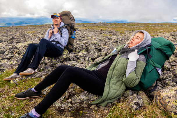 Podróż życia i przetrwania koncepcja lusterka. Piesze wycieczki kobiet i mężczyzn z plecaka są bardzo zmęczeni i leżą w obozowisku, ciesząc się trekking w górach tła. Koncepcja Wanderlust i podróży  - Zdjęcie, obraz