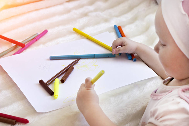 A little girl draws felt-tip pens on a blank sheet, - Фото, зображення