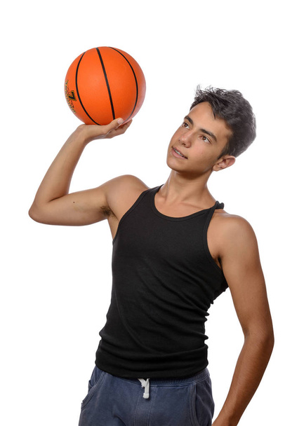 Portréja egy fiatal kosárlabdázó halad a labda. Fiatal fiú kaukázusi sportruházat kosarazik a fehér háttér, copyspace - Fotó, kép