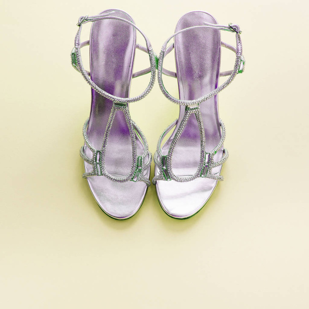 Fashionable womens sandals silver color on a yellow background. - Foto, Imagen