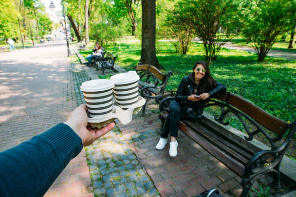 uomo portare il caffè per la giovane donna. data nel parco cittadino
. - Foto, immagini