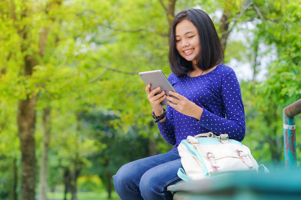 Asiática estudiante chica usando un digital tablet en el parque en un soleado verano día
 - Foto, imagen