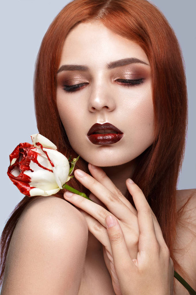Beautiful red-haired girl with a classic make-up and rose in her hands. Beauty face. - Valokuva, kuva