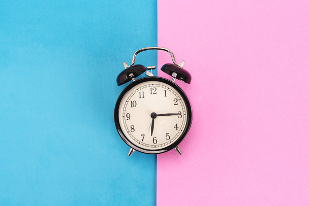 Vintage alarm clock on pink and blue background - Photo, image