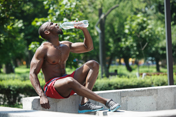 Athlete resting and drinking water after exercises at stadium - 写真・画像