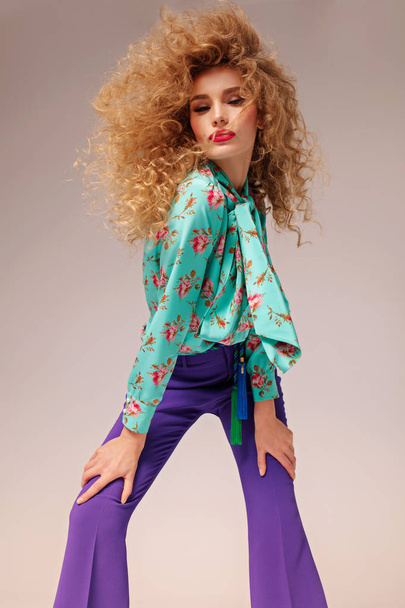 beauty portrait of young beautiful woman wearing green blouse with floral print and purple pants - Photo, Image