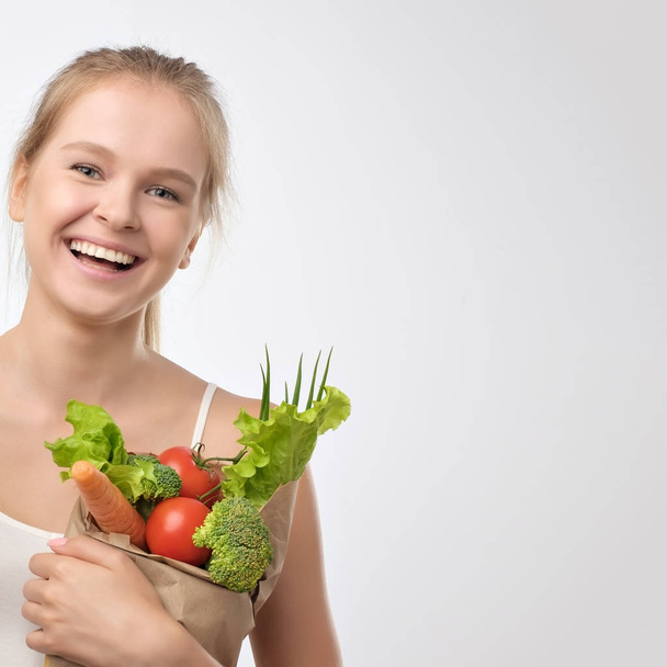 Giovane donna che tiene il sacchetto della spesa di carta alimentare pieno di verdure fresche. Dieta sana concetto di alimentazione
 - Foto, immagini