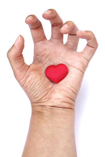 Hart in de hand. Grote rode hart in open palm van vrouw geïsoleerd op een witte achtergrond. Gebalde vingers. Symbool van de ongezonde liefde. - Foto, afbeelding