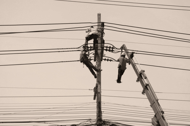 homens pendurados e trabalhando no poste elétrico
  - Foto, Imagem