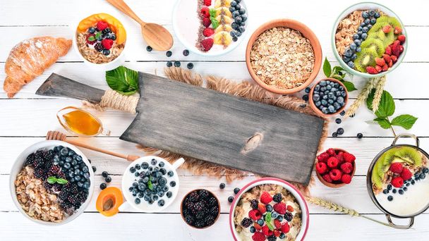 Large Assortment of porridge with fruit and berries. Breakfast. On a white wooden background. Top view. Free space for text. - 写真・画像