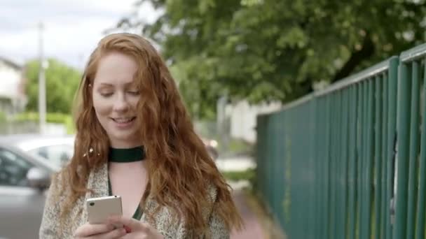 Mädchen geht auf die Straße und benutzt ein Mobiltelefon - Filmmaterial, Video