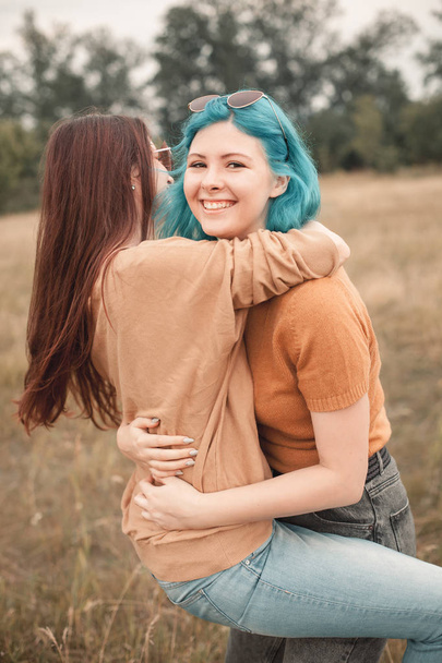Two young smiling friends hugging on field - Φωτογραφία, εικόνα