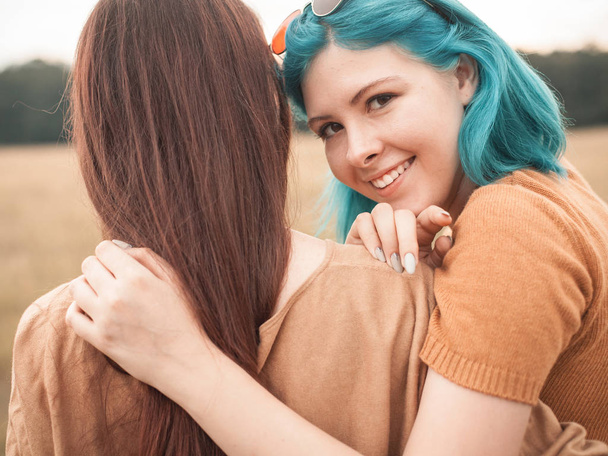 Two young smiling friends hugging on field - Photo, image