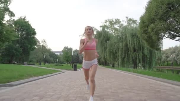 Portrait of handsome woman runing through the park in the morning during sunrise - Materiał filmowy, wideo