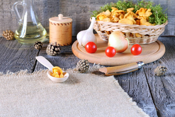 Fresh chanterelles and vegetables lie on the wooden table before cooking. - Фото, изображение