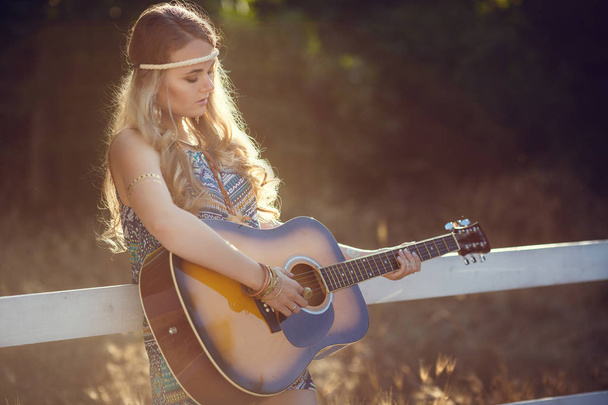 Beautiful hippie girl with guitar in park at sunset - Photo, Image