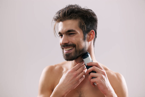 Junger Mann rasiert sich Bart mit Rasiermesser.  - Foto, Bild