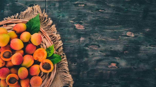 Fresh apricots with leaves On a black wooden background. Top view. Free space for your text. - Fotoğraf, Görsel