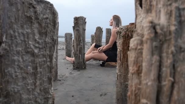 Young Blonde Woman Sittinf Surrounded with Stakes on the Coast of Salt Firth, Cloudy Weather - Footage, Video