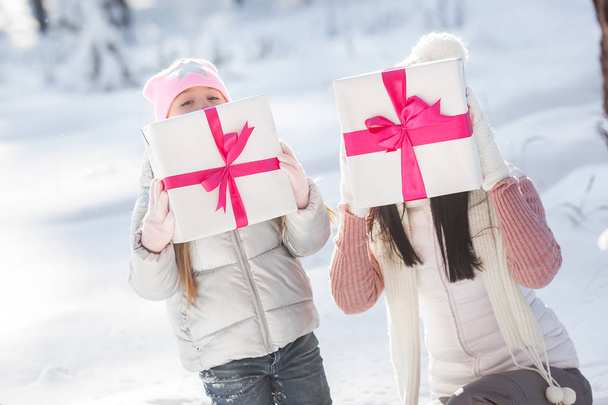 Die junge Mutter spielt mit ihrer kleinen Tochter im Schnee mit Weihnachtsgeschenken. Mädchen haben Spaß im Winter - Foto, Bild