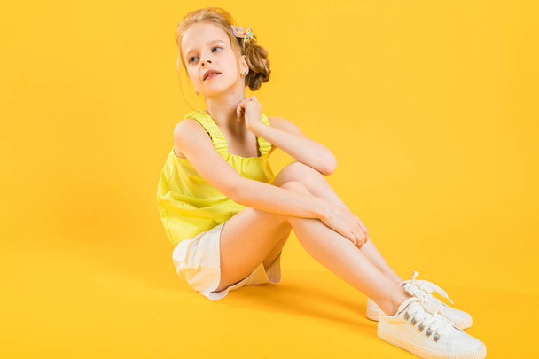 Una ragazza adolescente è seduta su uno sfondo giallo
. - Foto, immagini