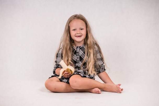 hermosa linda niña comiendo delicioso plátano saludable sobre fondo blanco
 - Foto, imagen