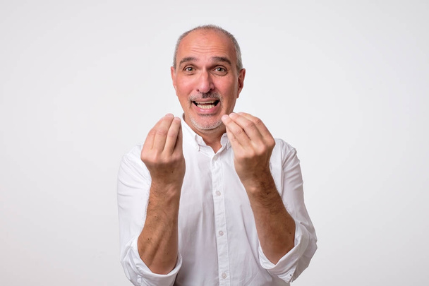 Portret van volwassen knappe man in een wit overhemd met Italiaanse gebaar - Foto, afbeelding