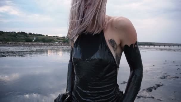 Очаровательная стройная блондинка, размазанная черной грязью, похожа на нефтяное масло
 - Кадры, видео