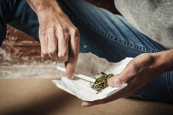 Drogově závislý si dělá cigaretu s marihuanou. Koncept užívání drog a obchodu s drogami. - Fotografie, Obrázek