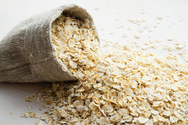 rolled oats in burlap bag on wood table - Foto, Imagem