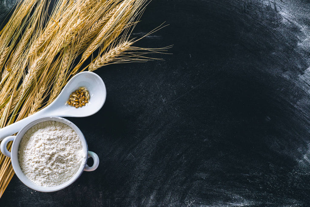Wheat ears and flour on black background - Zdjęcie, obraz
