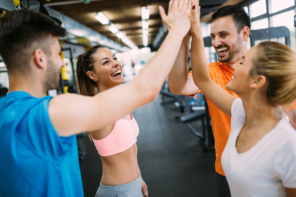 Smiling men and women doing high five in gym - Foto, afbeelding