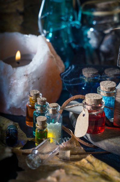 Magic concept. Potions in bottles, candles, box and orange leaves. Magical background - Photo, Image