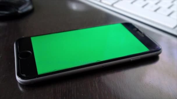 smartphone with green blank screen on wooden tabletop at home - Footage, Video