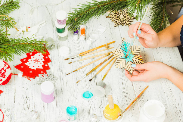 Decoraciones navideñas, pelotas, juguetes y cajas de regalo en una vieja tabla de madera. Las manos femeninas hacen decoraciones navideñas
. - Foto, Imagen
