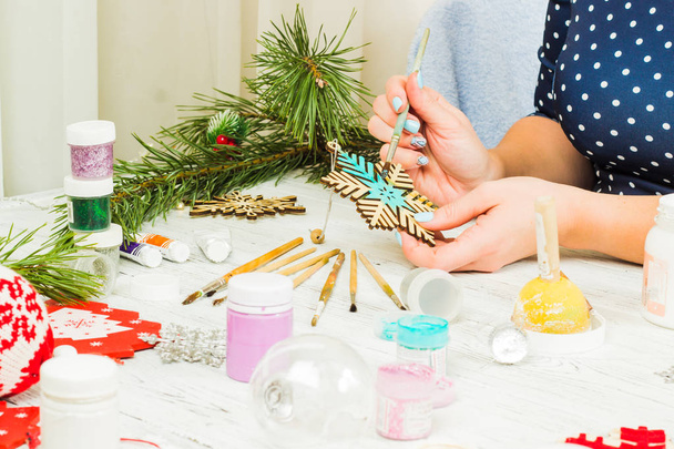 クリスマスの飾り、ボール、おもちゃ、古い木製ボード上のギフト ボックス。女性の手がクリスマスの飾り付けを作る. - 写真・画像