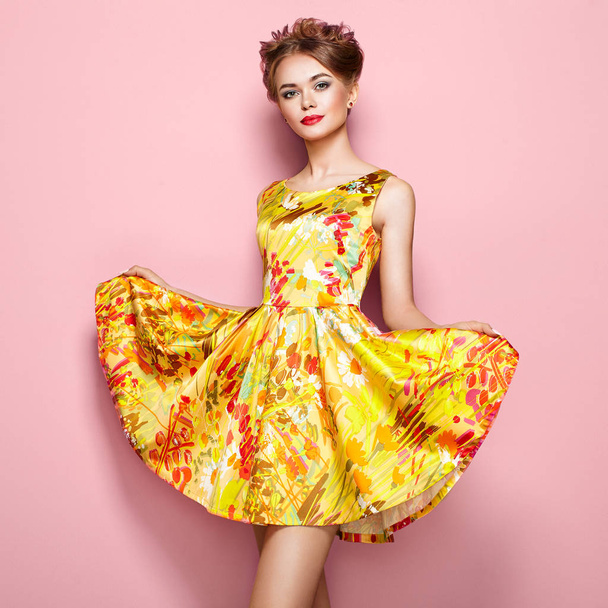 Portrait of Fashion Young woman in Floral Dress. Female model in Stylish Summer Outfit. Girl Posing on a Pink Background. Stylish Hairstyle. Fashion Photo. Blonde Lady - 写真・画像