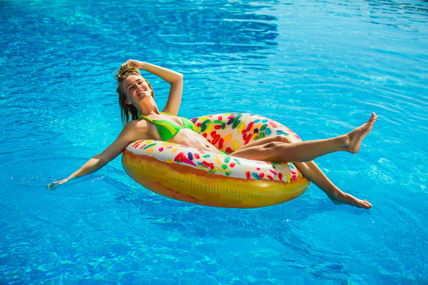 Onnellinen nainen bikineissä lepää puhallettavalla patjalla uima-altaassa, täyspitkä
 - Valokuva, kuva