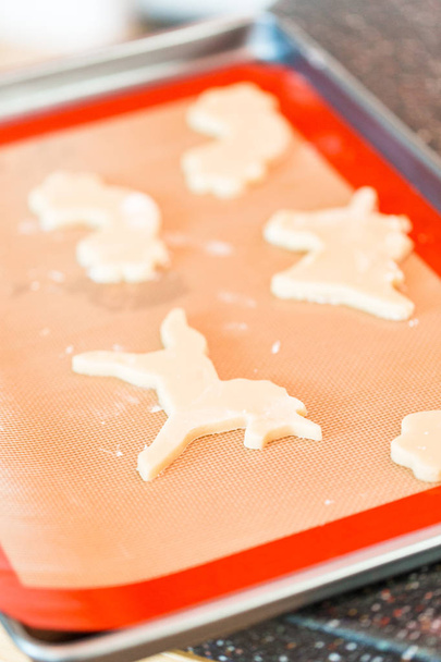Meisje uitrollen en uitsnijden van unicorn suiker koekjes. - Foto, afbeelding
