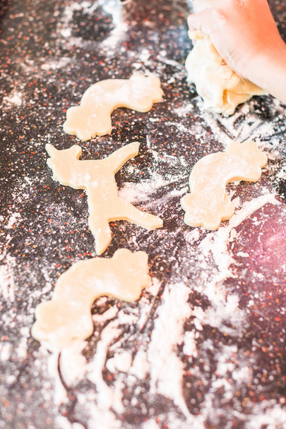 Little girl rolling out and cutting out unicorn sugar cookies. - Photo, Image