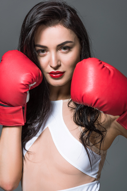 portrait of attractive boxer in white swimwear and boxing gloves isolated on grey - Foto, Imagen