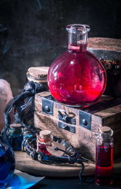 Conceito mágico. Poção vermelha em garrafa, velas, caixa de madeira. Fundo mágico
 - Foto, Imagem