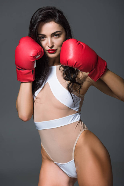 sexy bokser in witte badmode en bokshandschoenen geïsoleerd op grijs - Foto, afbeelding
