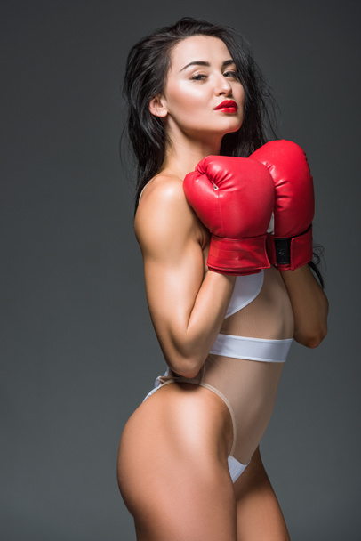 vista laterale di sexy donna sportiva in costume da bagno bianco e guanti da boxe isolati su grigio
 - Foto, immagini